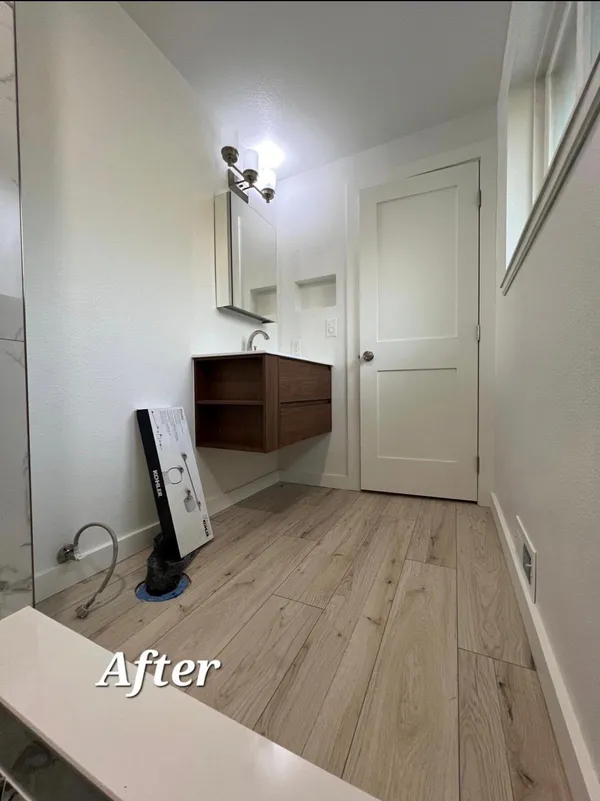 After photo of remodeled bathroom with floating walnut vanity, wood-look plank flooring, and updated lighting