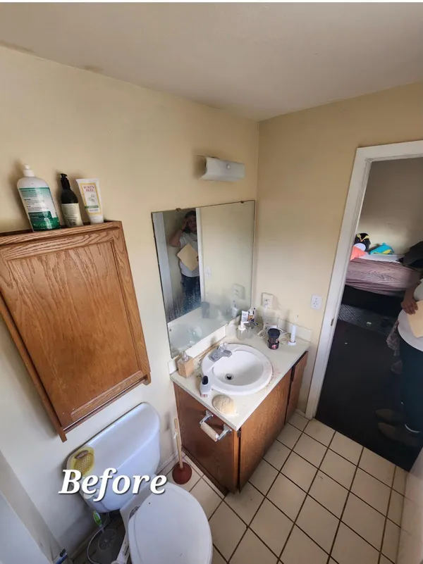Before photo of bathroom with oak vanity, ceramic tile floor, and dated fixtures prior to remodel