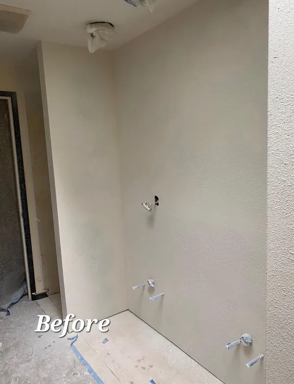 Before photo of bathroom remodel showing bare walls with plumbing rough-in prior to shower installation